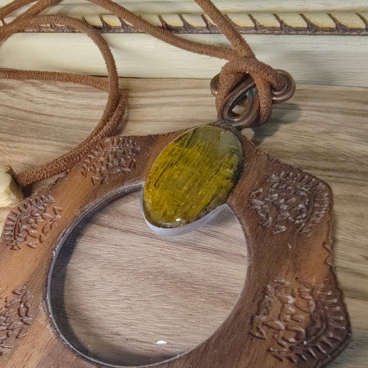 Magnifying glass necklace with nelite stone, mandala design, and adjustable leather cord.