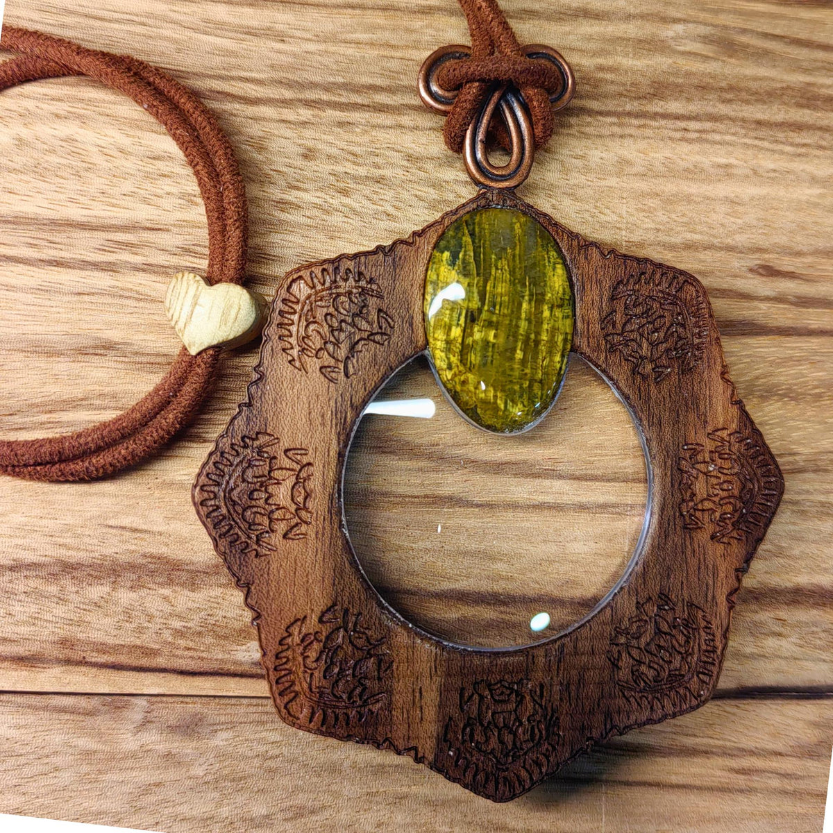 Magnifying glass necklace with nelite stone, mandala design, and adjustable leather cord.