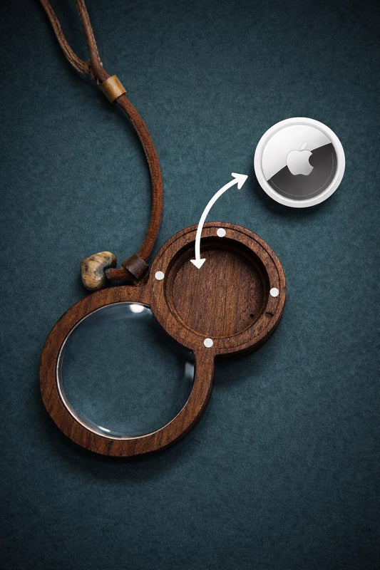Wooden magnifying glass pendant with hidden AirTag compartment for tracking device.
