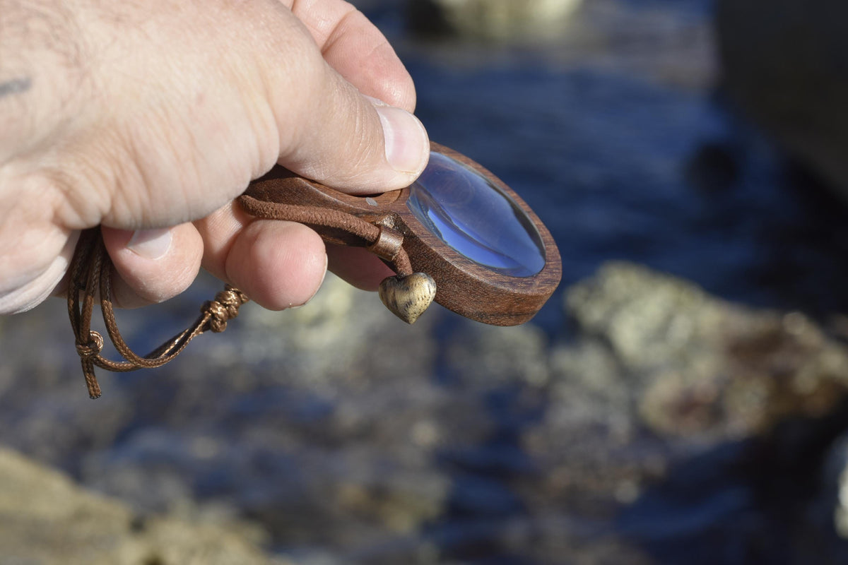 Wooden magnifying glass pendant with hidden AirTag compartment for tracking device.