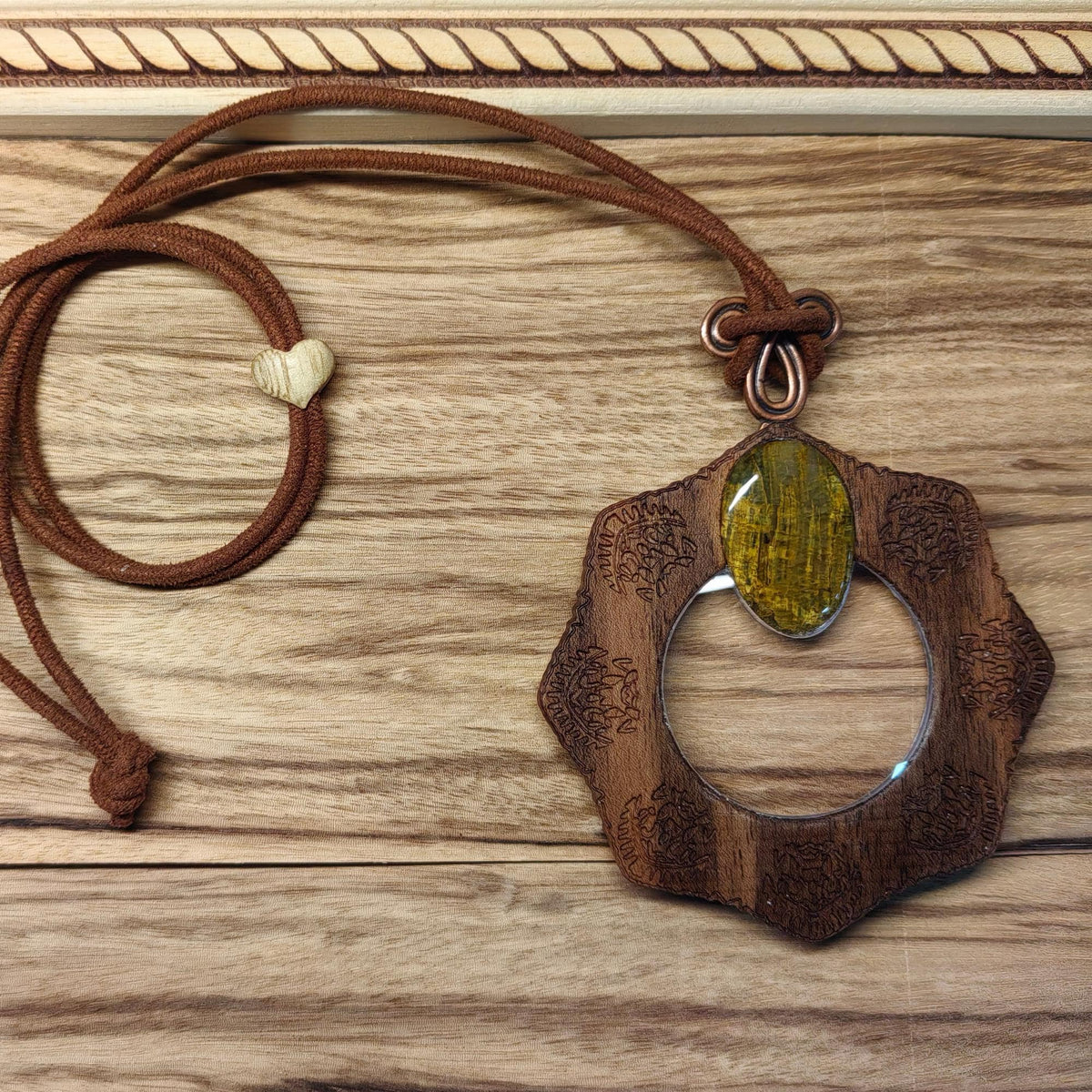 Magnifying glass necklace with nelite stone, mandala design, and adjustable leather cord.