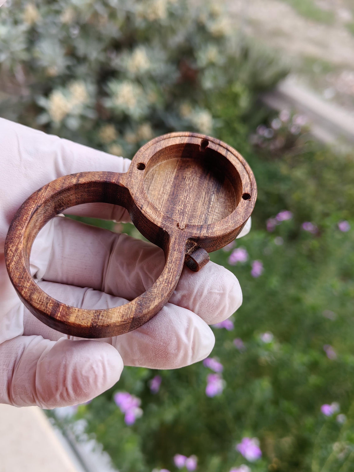 Wooden magnifying glass pendant with hidden AirTag compartment for tracking device.